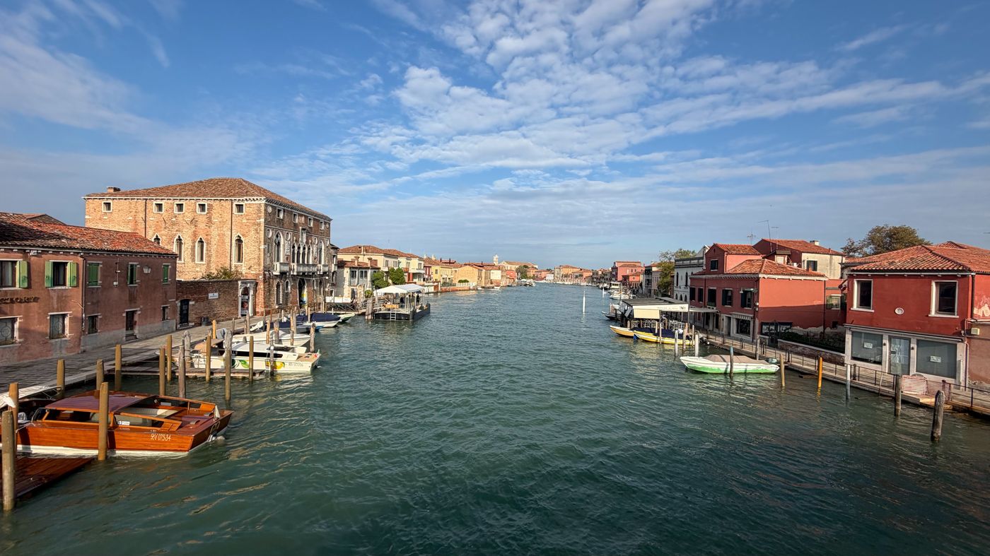 Colorful Burano homes lining a broad canal beneath a blue sky